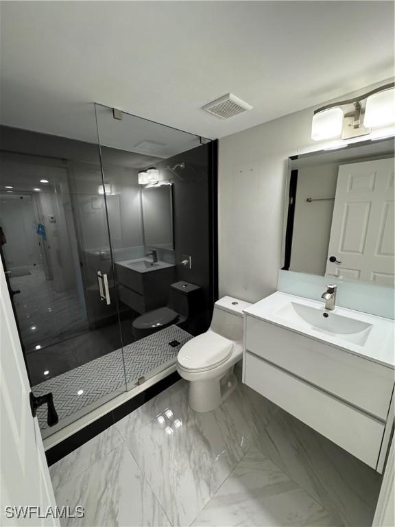 bathroom featuring vanity, a shower with shower door, and toilet