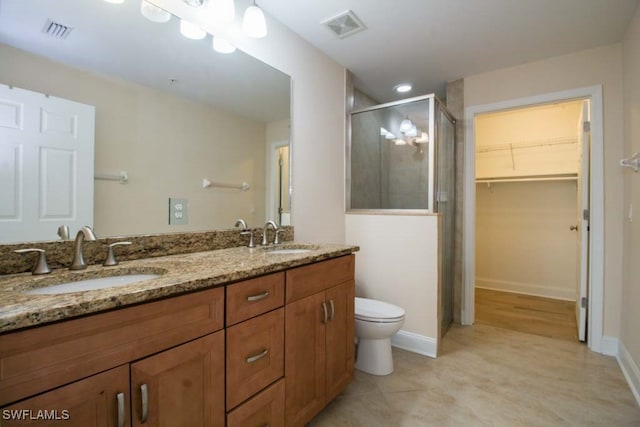 bathroom with tile patterned floors, vanity, toilet, and a shower with door