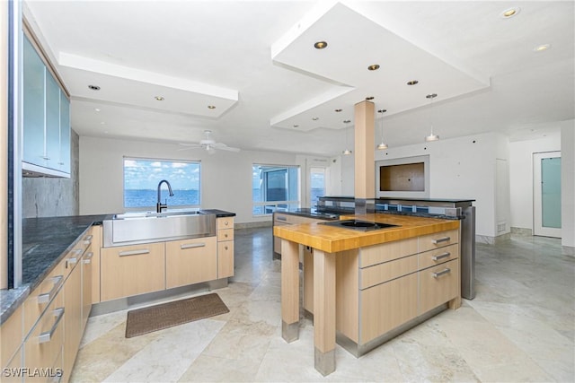 kitchen featuring a kitchen island, sink, light brown cabinets, and wooden counters