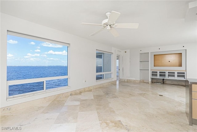 unfurnished living room with ceiling fan and a water view