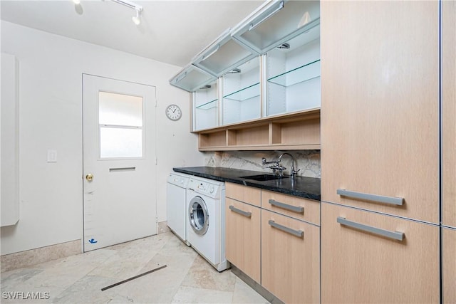 clothes washing area featuring cabinets, washing machine and dryer, and sink