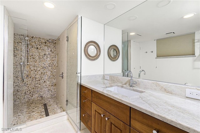 bathroom featuring tiled shower and vanity