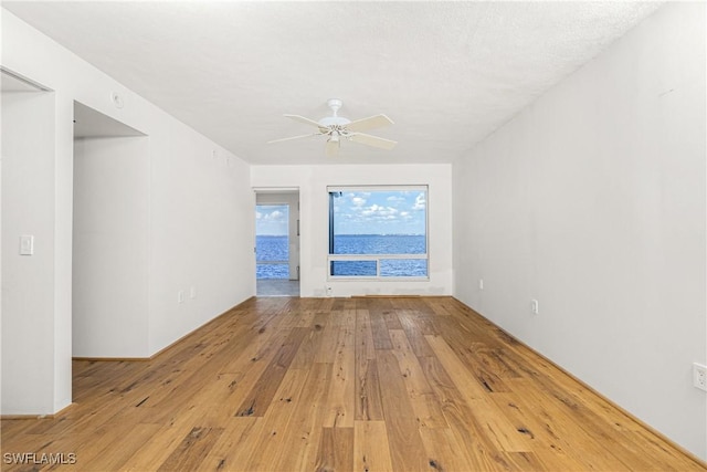 spare room with ceiling fan, a textured ceiling, and light wood-type flooring