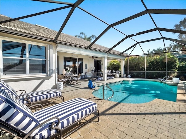 view of pool featuring a patio, glass enclosure, and ceiling fan