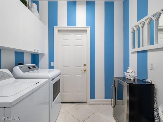 washroom featuring cabinets, washing machine and dryer, and light tile patterned floors