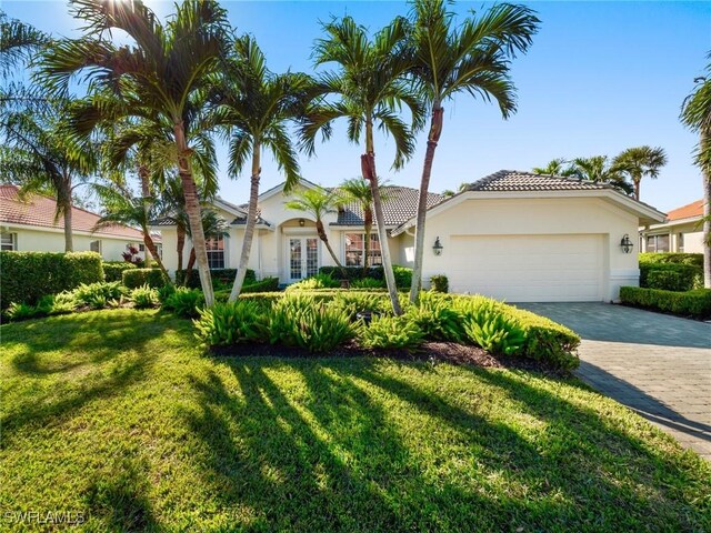 mediterranean / spanish-style house with a garage, a front yard, and french doors