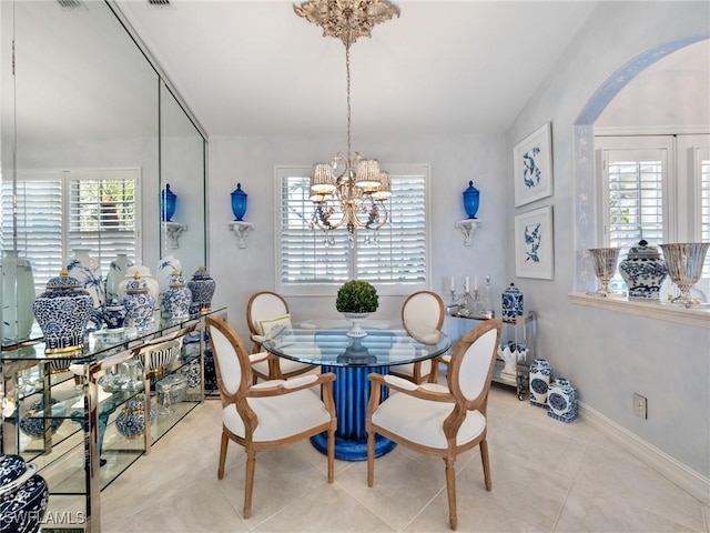 tiled dining space featuring a wealth of natural light and a notable chandelier