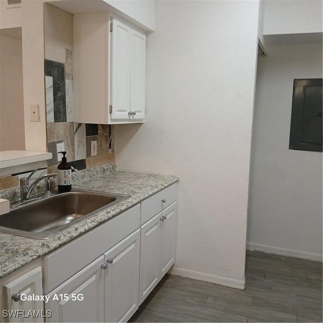 kitchen with electric panel, white cabinetry, dark hardwood / wood-style floors, and sink