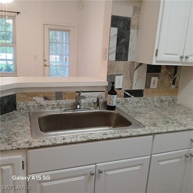 interior space featuring white cabinets, backsplash, and sink