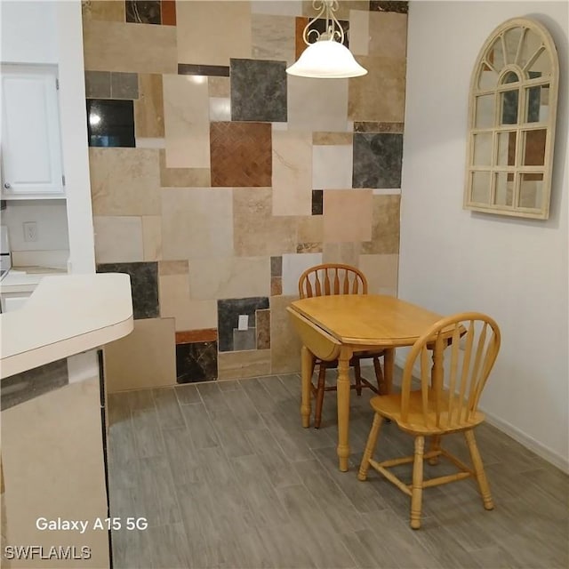 dining area with light hardwood / wood-style flooring and tile walls