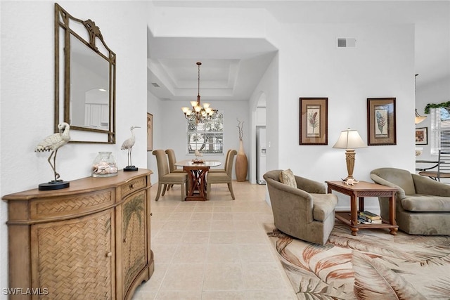 interior space featuring a raised ceiling, light tile patterned flooring, and a chandelier