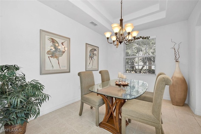 tiled dining area featuring a tray ceiling and a chandelier