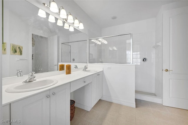 bathroom with tile patterned flooring, a tile shower, and vanity