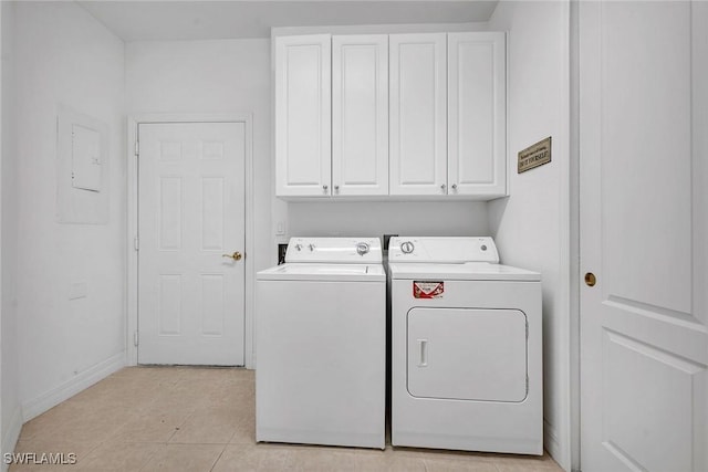 washroom featuring cabinets, light tile patterned floors, electric panel, and washing machine and clothes dryer