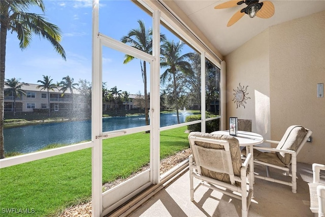 sunroom featuring ceiling fan, a water view, and vaulted ceiling