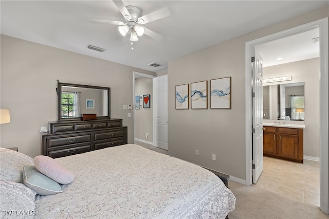 bedroom featuring ensuite bath, light colored carpet, and ceiling fan