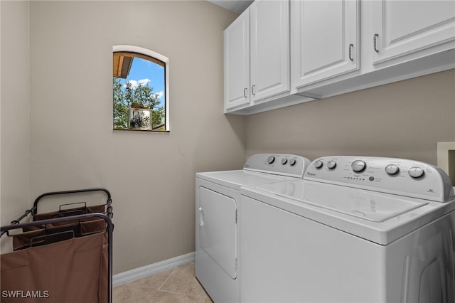 washroom with light tile patterned floors, washing machine and dryer, and cabinets