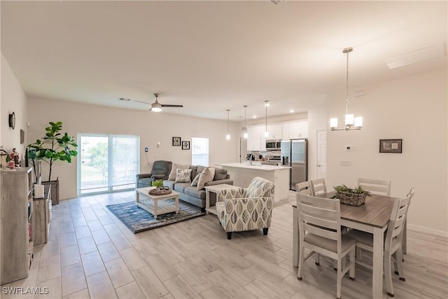 living room featuring ceiling fan with notable chandelier, light wood-type flooring, and recessed lighting