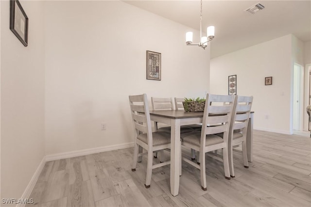 dining space featuring baseboards, light wood-style flooring, visible vents, and a notable chandelier