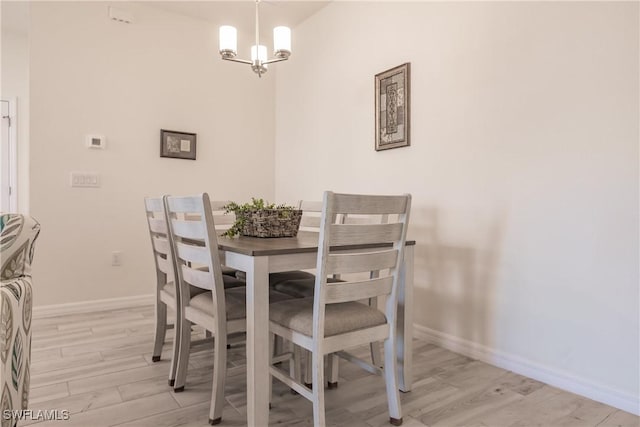 dining area with baseboards, light wood finished floors, and an inviting chandelier