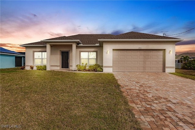 view of front of home featuring decorative driveway, an attached garage, a lawn, and stucco siding