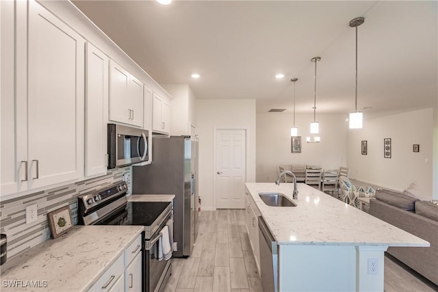 kitchen featuring stainless steel appliances, a kitchen island with sink, white cabinetry, and a sink