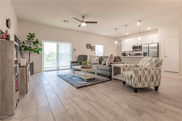 living room featuring visible vents, ceiling fan, and light wood finished floors