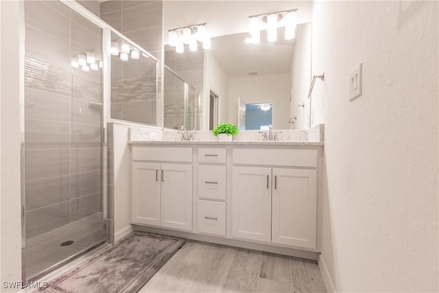 bathroom featuring double vanity, a stall shower, and a sink