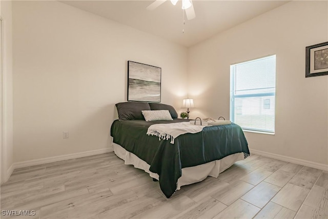 bedroom with ceiling fan, light wood finished floors, and baseboards