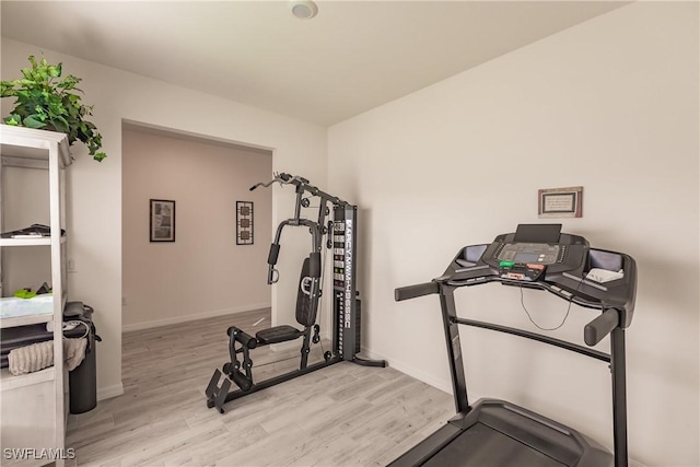 exercise room featuring light wood finished floors and baseboards