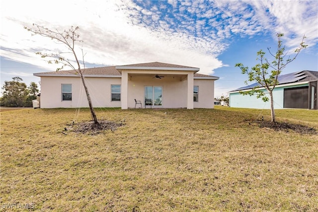 rear view of house featuring a yard, a ceiling fan, and stucco siding