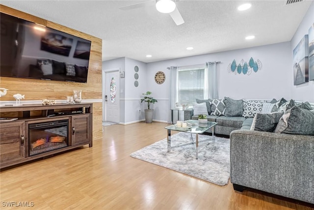 living room featuring a textured ceiling, light hardwood / wood-style floors, and ceiling fan