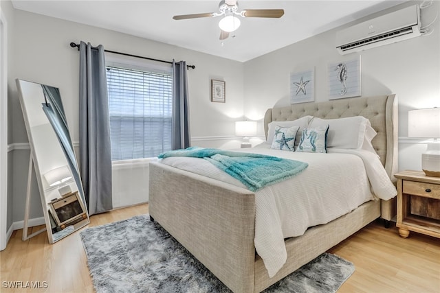 bedroom featuring hardwood / wood-style flooring, a wall mounted AC, and ceiling fan