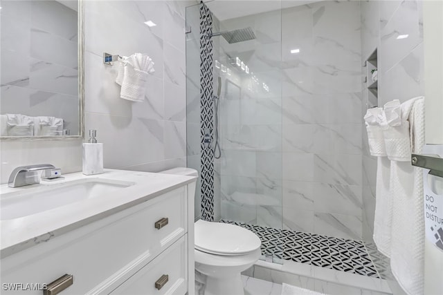 bathroom with a tile shower, vanity, and toilet