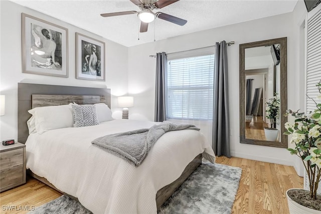 bedroom featuring ceiling fan, a textured ceiling, and light wood-type flooring