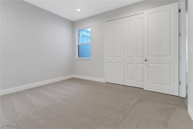 unfurnished bedroom featuring light colored carpet and a closet