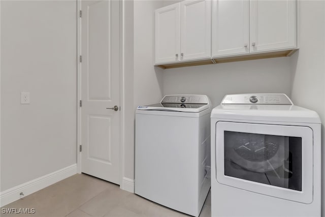 clothes washing area featuring cabinets, independent washer and dryer, and light tile patterned floors