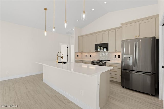 kitchen with sink, decorative light fixtures, appliances with stainless steel finishes, an island with sink, and backsplash