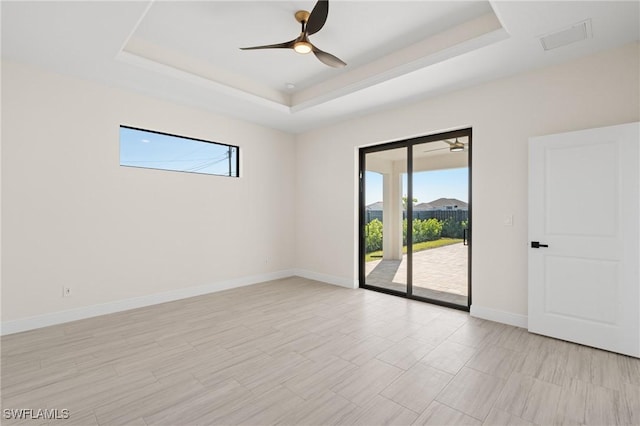 unfurnished room with ceiling fan, a tray ceiling, and a wealth of natural light