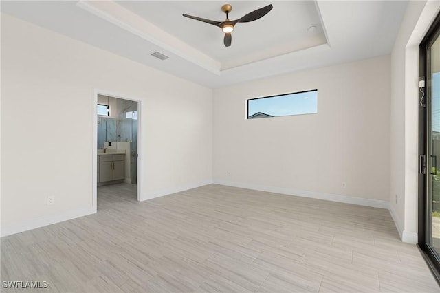 unfurnished room with ceiling fan and a tray ceiling