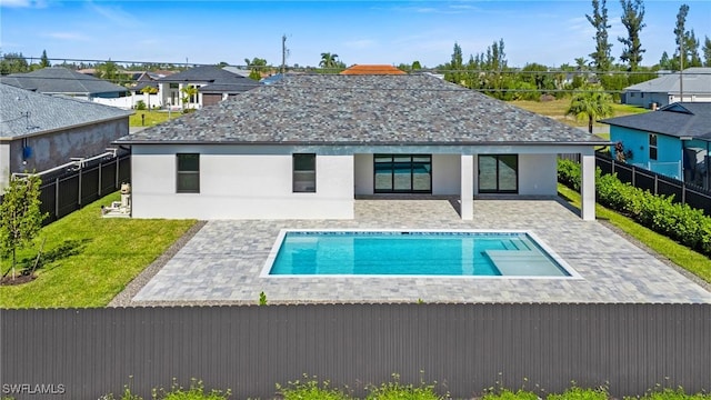 back of property with a fenced in pool and a patio