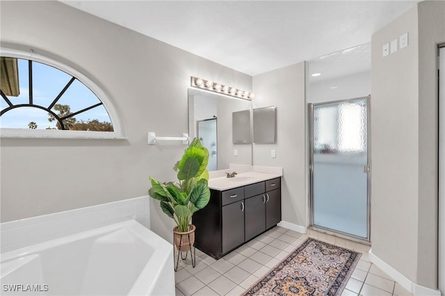 full bathroom with a garden tub, a shower stall, tile patterned flooring, baseboards, and vanity