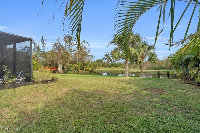 view of yard featuring a water view and glass enclosure