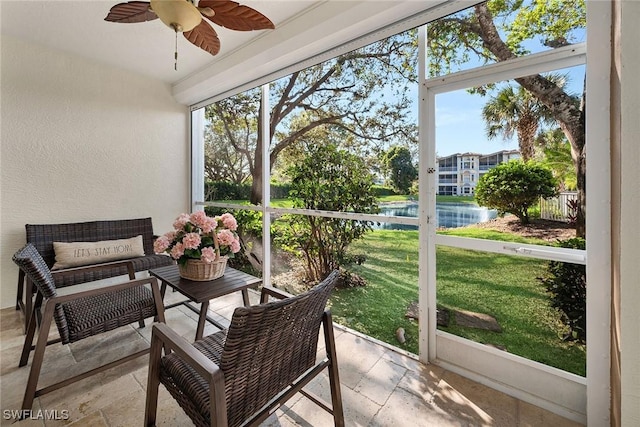 sunroom featuring ceiling fan, a water view, and a wealth of natural light