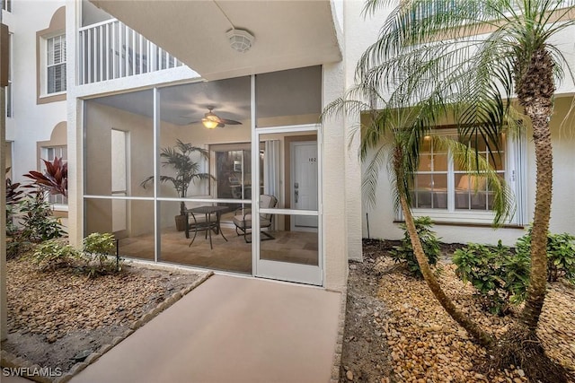 entrance to property featuring ceiling fan, a balcony, and a patio