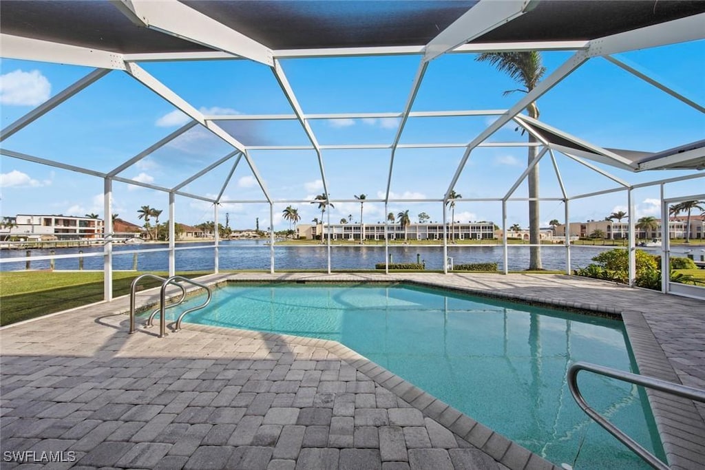 view of swimming pool featuring glass enclosure, a water view, and a patio