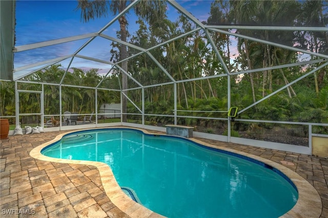 pool at dusk with a lanai and a patio area