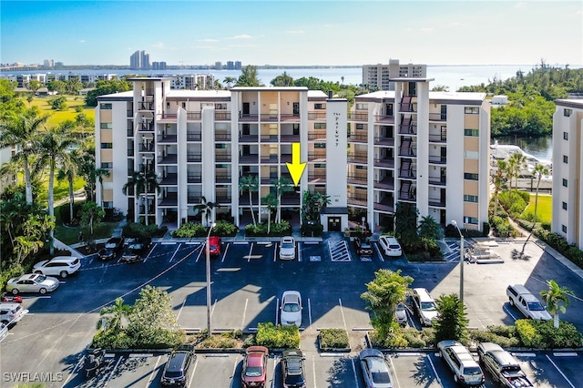 view of building exterior featuring uncovered parking, a view of city, and a water view