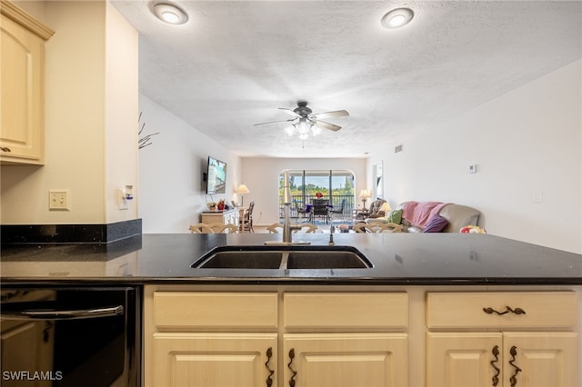 kitchen with open floor plan, a peninsula, a textured ceiling, and a sink