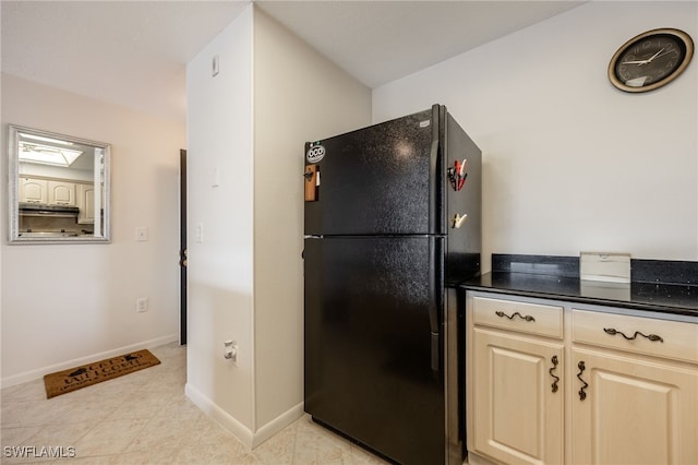 kitchen with light tile patterned floors, under cabinet range hood, freestanding refrigerator, and baseboards